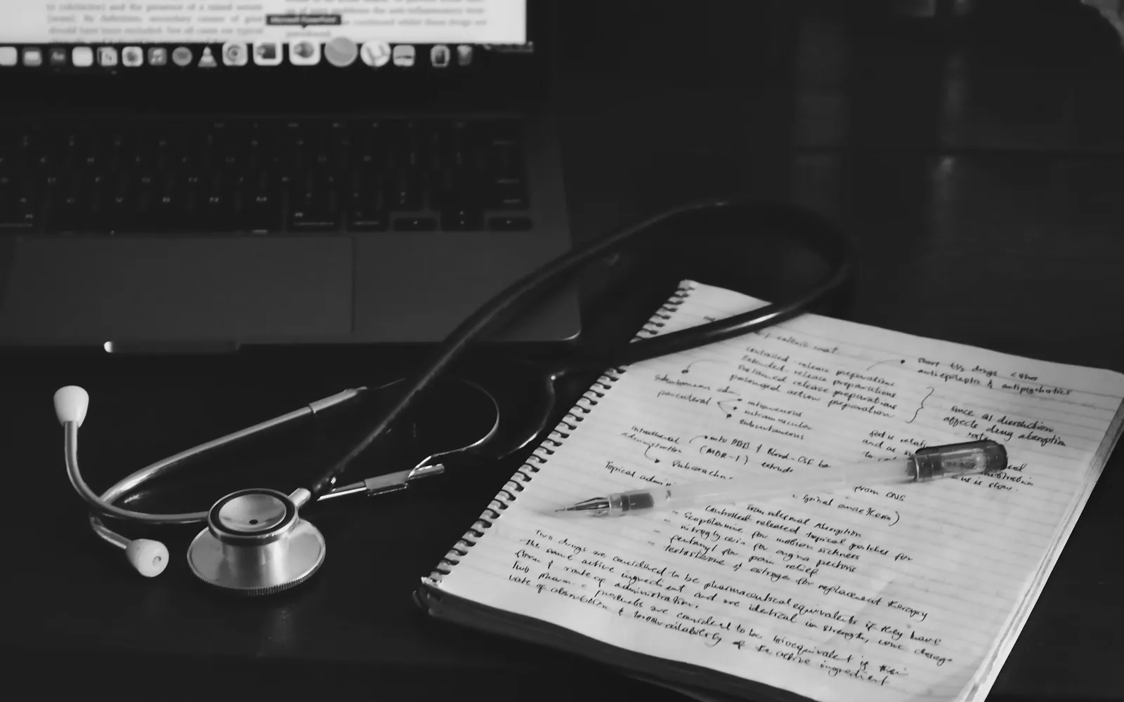 Stéthoscope posé sur un carnet de notes à côté d’un ordinateur.